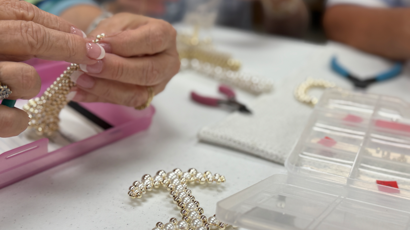 Senior resident assembling a beaded cross during a jewelry making activity in a senior living community.