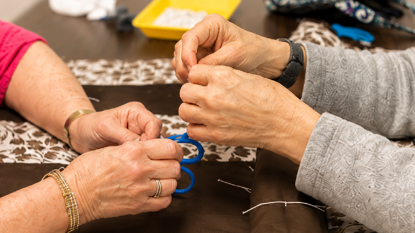 Quilt Ministry volunteers tying a handmade prayer quilt together before it is given to someone in need.